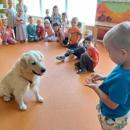 Spotkanie edukacyjne w przedszkolu Sezamkowe, dzieci obserwują psa podczas zajęć z elementami edukacji społecznej.