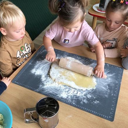 Zajęcia kulinarne w przedszkolu Sezamkowe, dzieci wałkują ciasto i rozwijają umiejętności manualne.