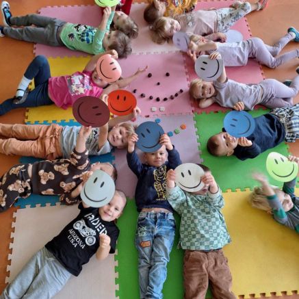 Zajęcia rozwijające rozpoznawanie emocji w przedszkolu Sezamkowe, dzieci leżą na matach i pracują z symbolami.