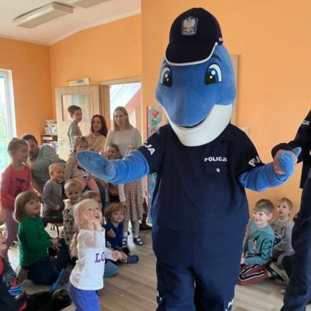 Spotkanie edukacyjne w przedszkolu Sezamkowe z udziałem maskotki policyjnej i grupy dzieci.